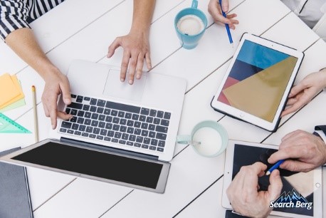 group of people have a discussion while using their electronic devices 